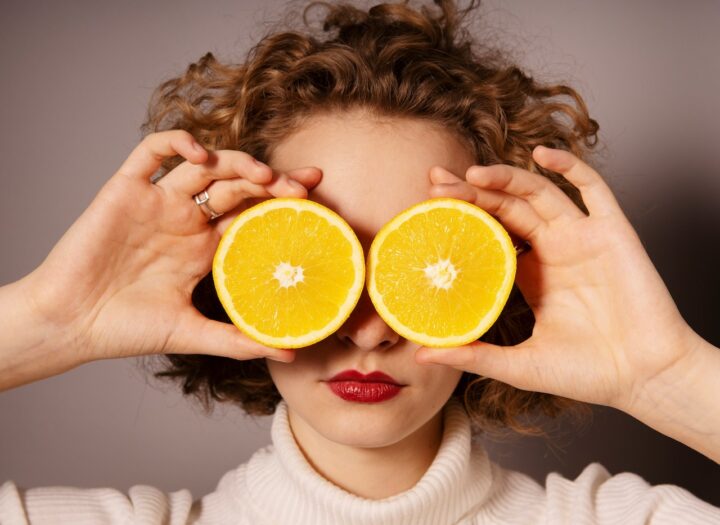 オレンジを顔の前に置いている女性